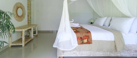 A bedroom with a bed, white canopy, bedside table, and a mirror.