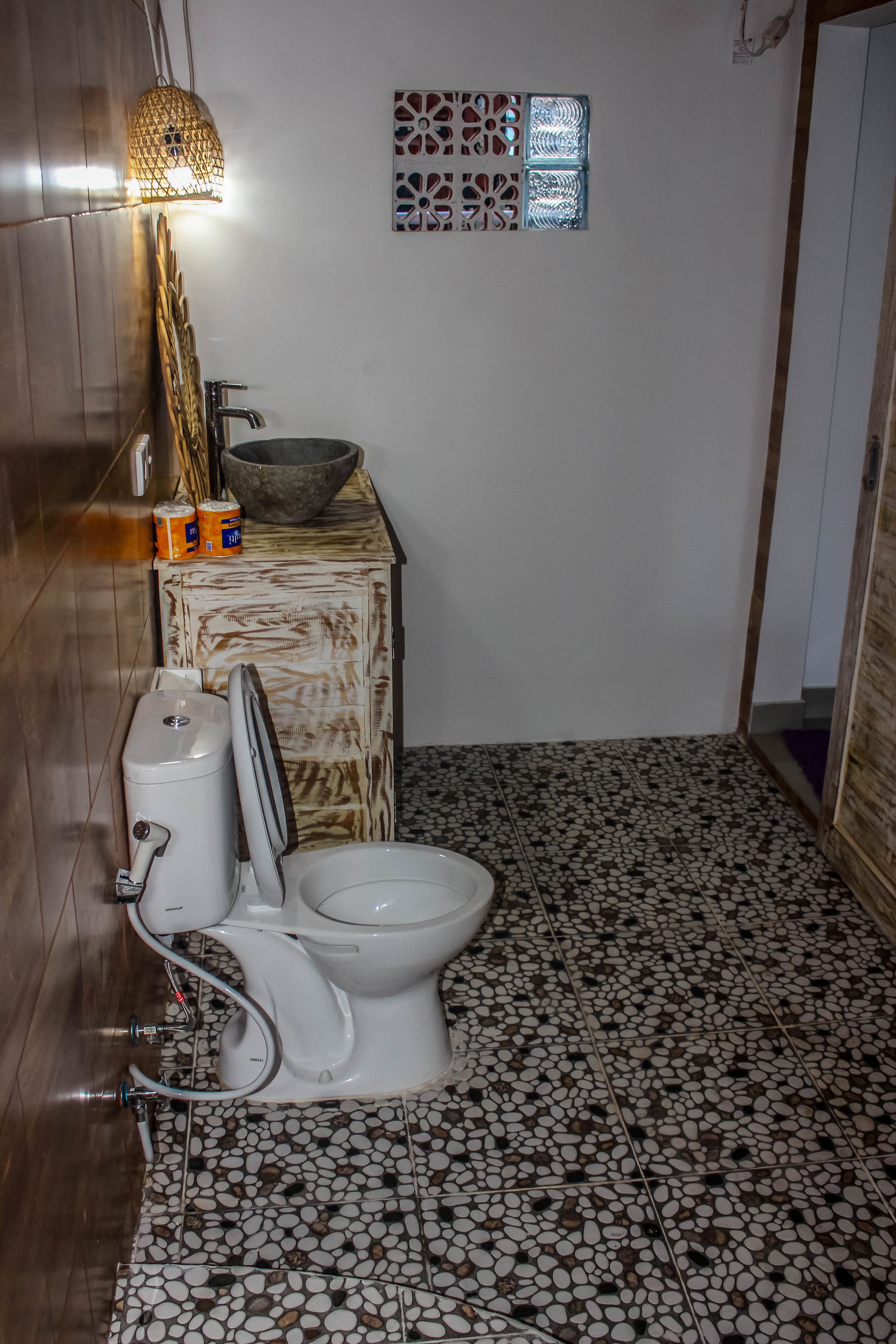 A bathroom with a toilet, a sink, and a decorative wall piece.