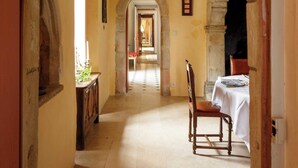A corridor with an arched ceiling, a dining table with chairs, and a fireplace.