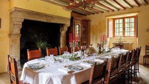A dining room with a long table set for a meal, a fireplace, and a window with natural light.