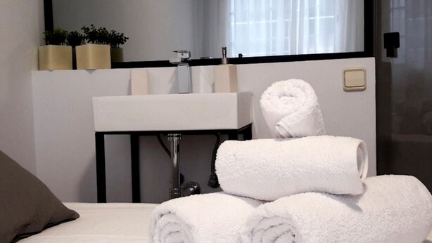 A hotel room with a bed, a white sink, and a mirror. There are towels on the bed and a plant on the wall. - Apartment in the historic center with pool and fireplace for winter (SEVILLA)
