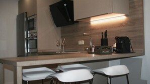A modern kitchen with a wooden countertop, stainless steel appliances, and bar stools. - Apartment in the historic center with pool and fireplace for winter (SEVILLA)