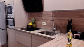 A modern kitchen with stainless steel appliances, a double sink, and a wine glass on the counter. - Apartment in the historic center with pool and fireplace for winter (SEVILLA)