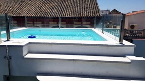 A rectangular swimming pool with a glass railing, a blue float, and steps leading up to it. - Apartment in the historic center with pool and fireplace for winter (SEVILLA)