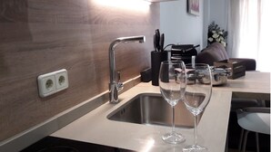 A modern kitchen with a stainless steel sink, a double electrical outlet, and a coffee machine on the counter. - Apartment in the historic center with pool and fireplace for winter (SEVILLA)