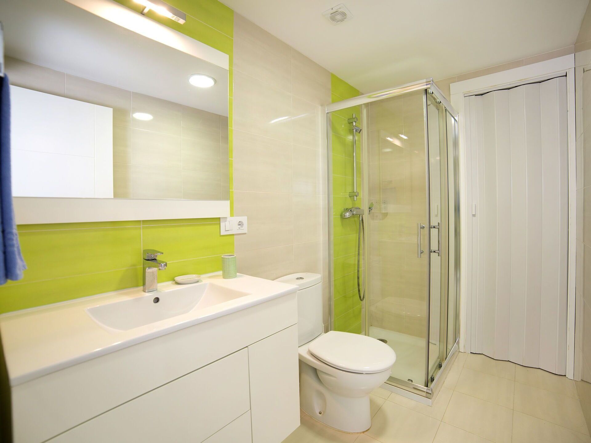 A modern bathroom with a glass-enclosed shower, a white sink, and a toilet.