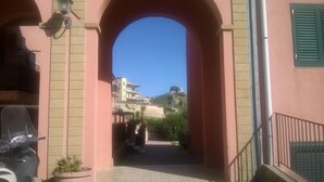 Una entrada arqueada a un edificio, con vistas despejadas a una colina y edificios modernos al fondo.