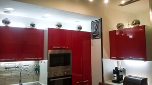 Una cocina con armarios rojos, horno integrado y cafetera.