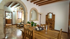 A dining area with a wooden table and chairs, an archway, and a view into the kitchen. - Wonderful private villa for 4 people with A/C, WIFI, TV and terrace (Alcúdia)