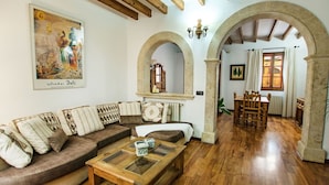 A cozy living room with a wooden floor, a brown sofa with patterned cushions, a glass-top coffee table, and a fireplace. - Wonderful private villa for 4 people with A/C, WIFI, TV and terrace (Alcúdia)