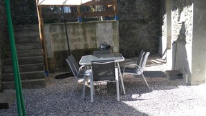 An outdoor patio area with a table and chairs, a pergola with a white umbrella, and a stone wall in the background. - RENTAL DOMAINE DE LA BAUME - "LE MOULIN" (Cendras)