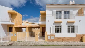 A modern residential building with a flat roof, white exterior walls, and a balcony.