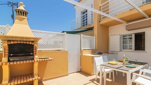 A patio with a built-in grill, a dining table with chairs, and a window with a view of the sky.
