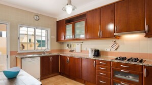 A kitchen with wooden cabinets, a countertop, a sink, a stove, and a window.
