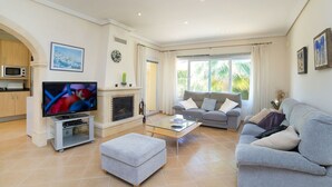 A modern living room with a flat-screen TV, grey sofas, a glass coffee table, and a fireplace. - Wonderful private villa for 6 guests with private pool, WIFI, A/C, TV and terrace (Benissa)