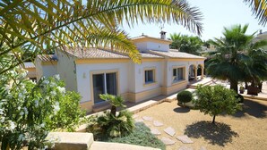 A two-story house with a tiled roof, a small front porch, and a garden with palm trees and flowering plants. - Wonderful private villa for 6 guests with private pool, WIFI, A/C, TV and terrace (Benissa)