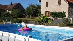 A residential swimming pool with a person floating on a pink floatation device.