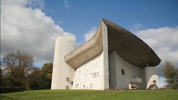 Ein modernes Gebäude mit einzigartigem architektonischen Design, das ein großes, sich überhängendes Dach und eine zylindrische Struktur aufweist.