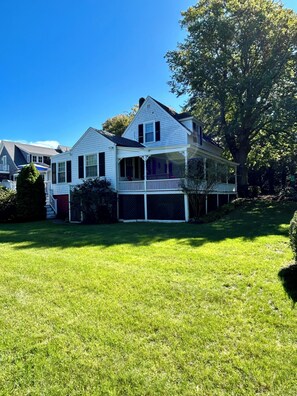 A two-story house with a front porch and a large tree in the yard. - Historic Edgartown House (Edgartown)