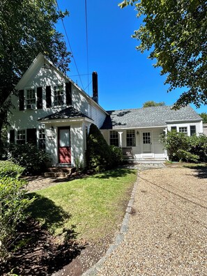 A two-story white house with a red door, a chimney, and a well-maintained lawn. - Historic Edgartown House (Edgartown)