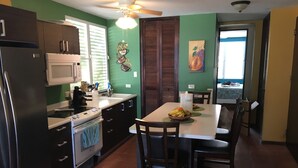 A kitchen with a microwave, stove, sink, and a dining table with chairs.