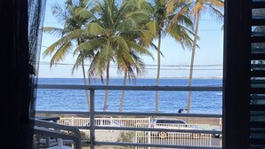 A view from a balcony overlooking palm trees and the ocean.