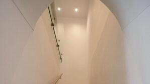 Eine Treppe mit Handlauf, die zu einer Zwischenebene mit gewölbter Decke und eingelassener Beleuchtung führt.