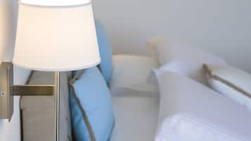 Een bed met wit beddengoed en een lamp met een witte lampenkap.