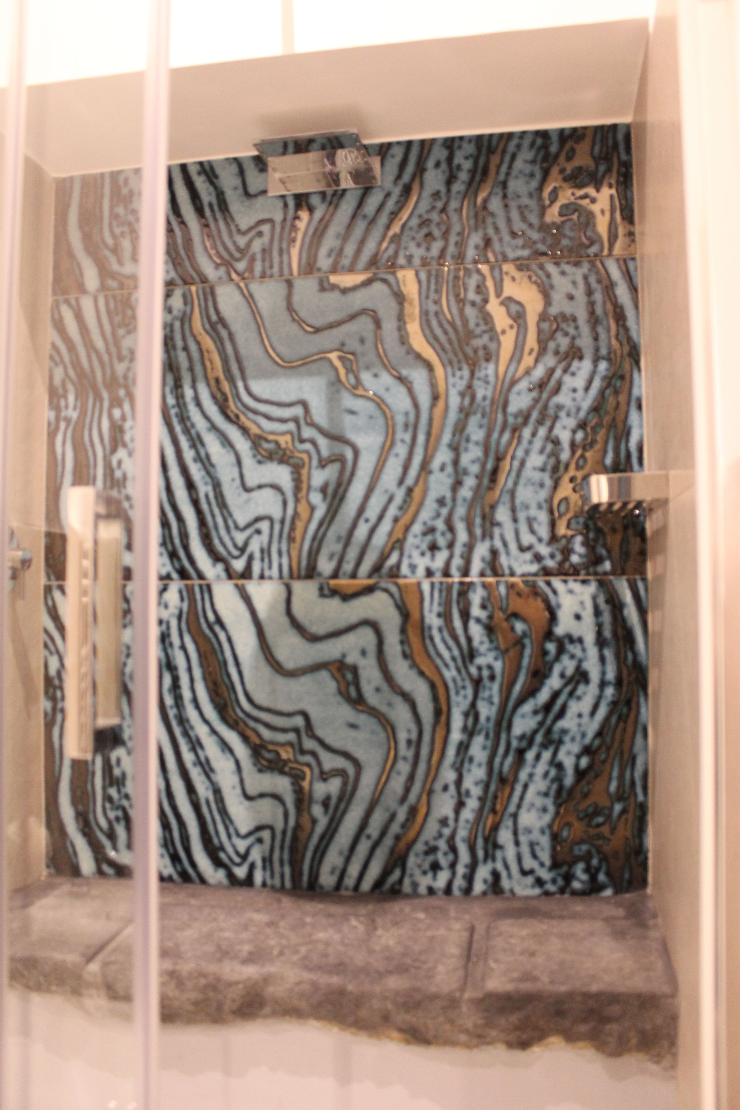 Baño con pared de mármol y cabina de ducha de vidrio.