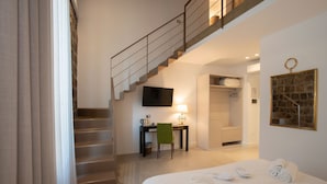Ein Hotelzimmer mit Bett, Schreibtisch, Stuhl, Fernseher, Treppe und Badezimmer.