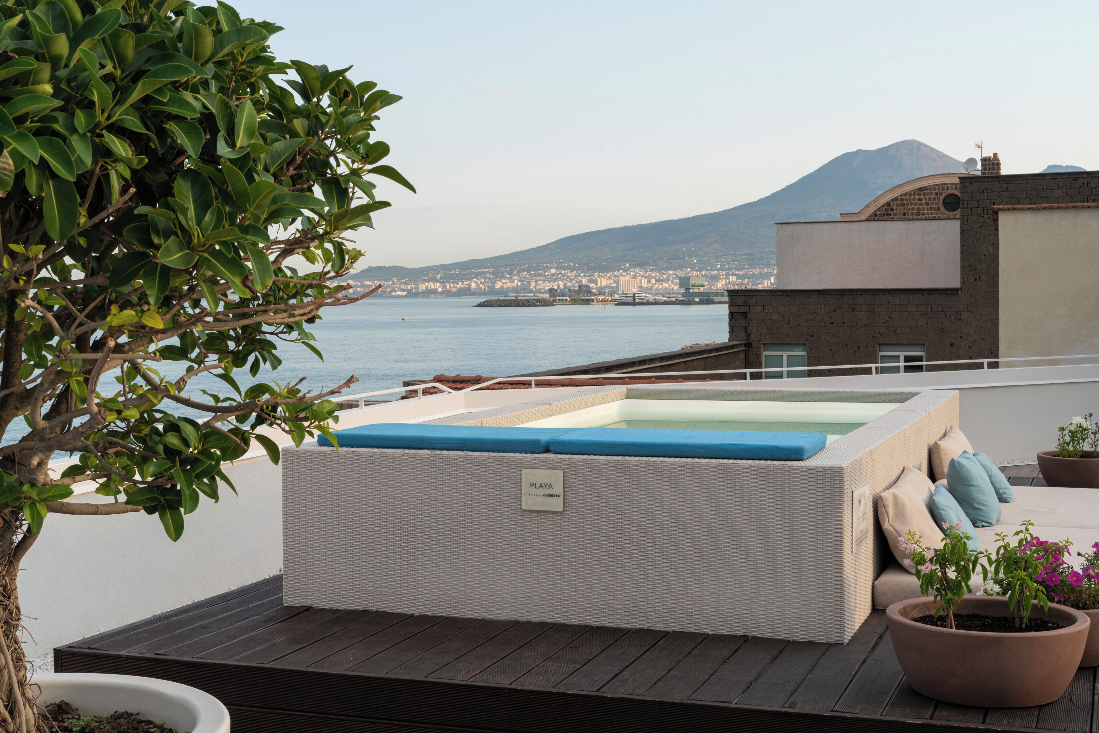 Eine Dachterrasse mit Whirlpool, Sitzgelegenheit und Blick auf Stadt und Berge.