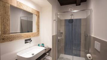 Ein modernes Badezimmer mit einem großen, weißen Waschbecken, einer in Glas eingefassten Dusche und einer Holzvertäfelung über dem Spiegel.