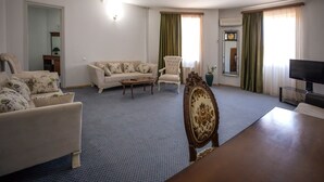 Una sala de estar con sofá, sillones, una mesa de centro, televisor y un espejo decorativo.