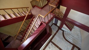Una escalera de varios niveles con barandillas de madera y peldaños alfombrados de color rojo.