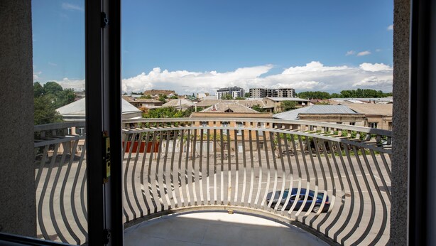 Un balcón con vista a un estacionamiento y edificios al fondo.
