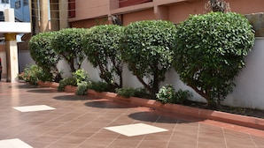 A tiled courtyard with neatly trimmed hedges along a wall. - Cascadehotel (Accra)