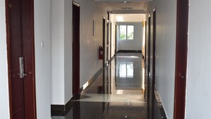 A hallway with polished black marble floors, white walls, and wooden doors. - Cascadehotel (Accra)