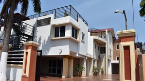 A modern building with a white facade, a balcony, and a gated entrance. - Cascadehotel (Accra)
