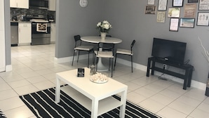 Un salon moderne avec une table blanche, un tapis à rayures noires et blanches et un meuble pour la télévision.