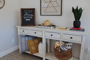 A white dresser with a chalkboard sign, a hat, a plant, and books.