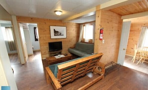 Ein Holzinnenraum mit einer Couch, einem Fernseher und einem gerahmten Bild an der Wand.