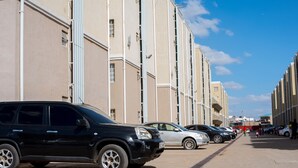 A row of parked cars along a street with buildings on one side.