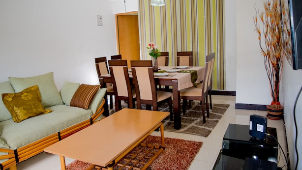 A living room with a sofa, a dining table with chairs, a coffee table, and a TV stand.