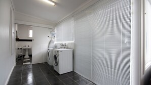 A laundry room with a washing machine, dryer, and ironing board.