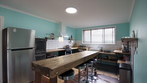A kitchen with a wooden bar, stainless steel appliances, and teal walls.