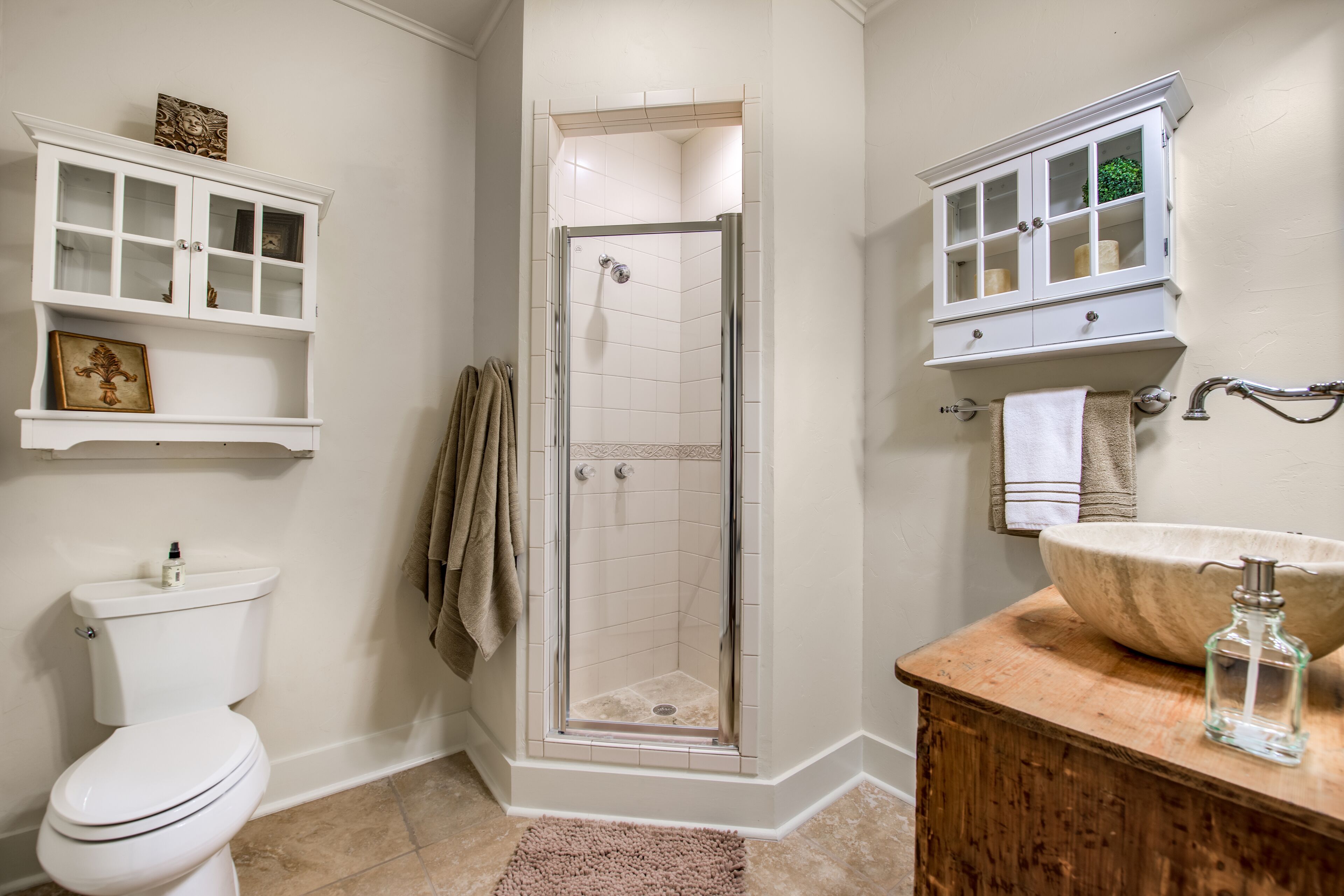 Une salle de bain comprenant des toilettes, une douche, un meuble-lavabo et des placards.