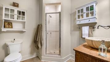 Une salle de bain comprenant des toilettes, une douche, un meuble-lavabo et des placards.