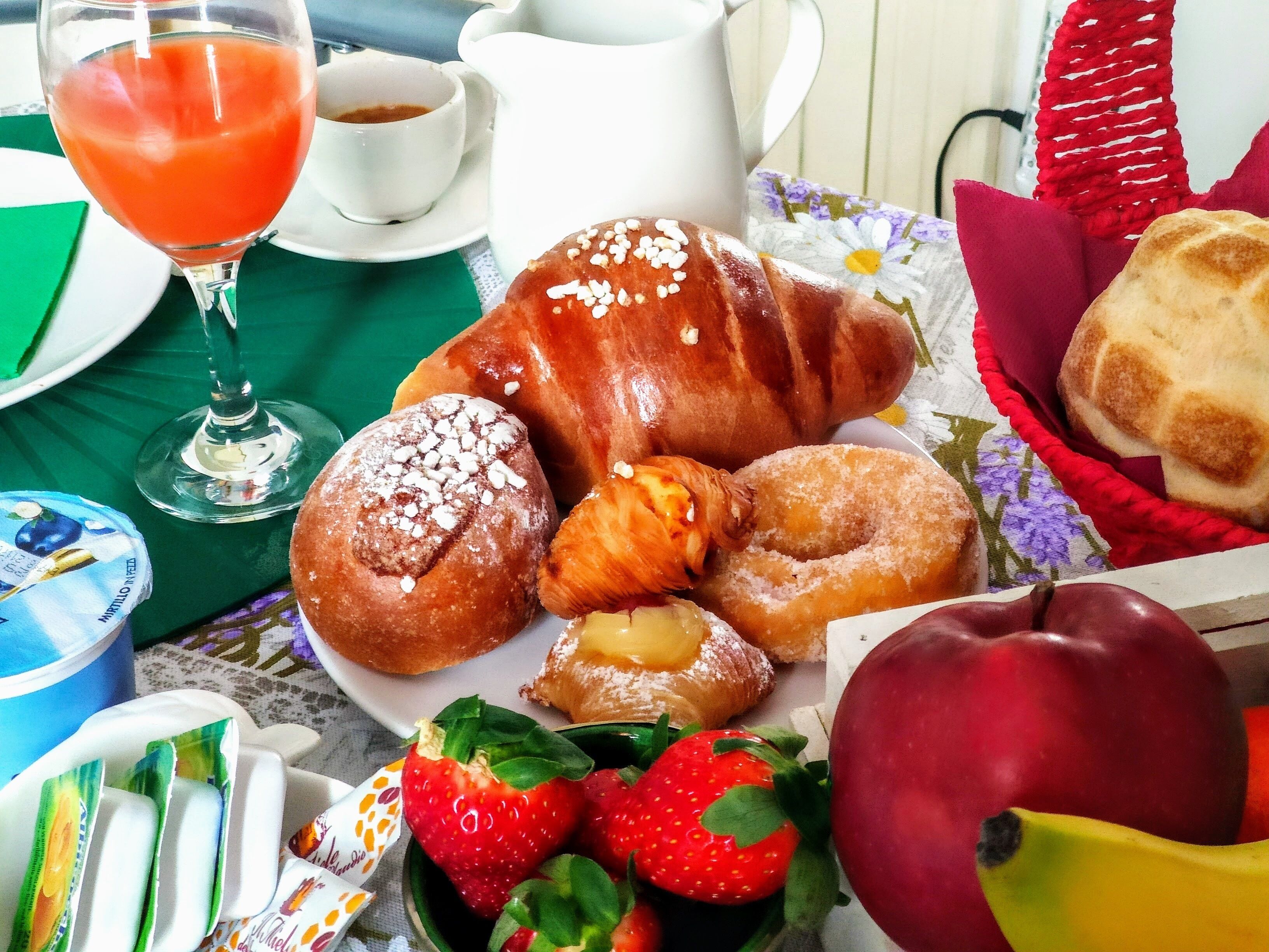 A breakfast setting with pastries, a glass of juice, and fresh fruit.