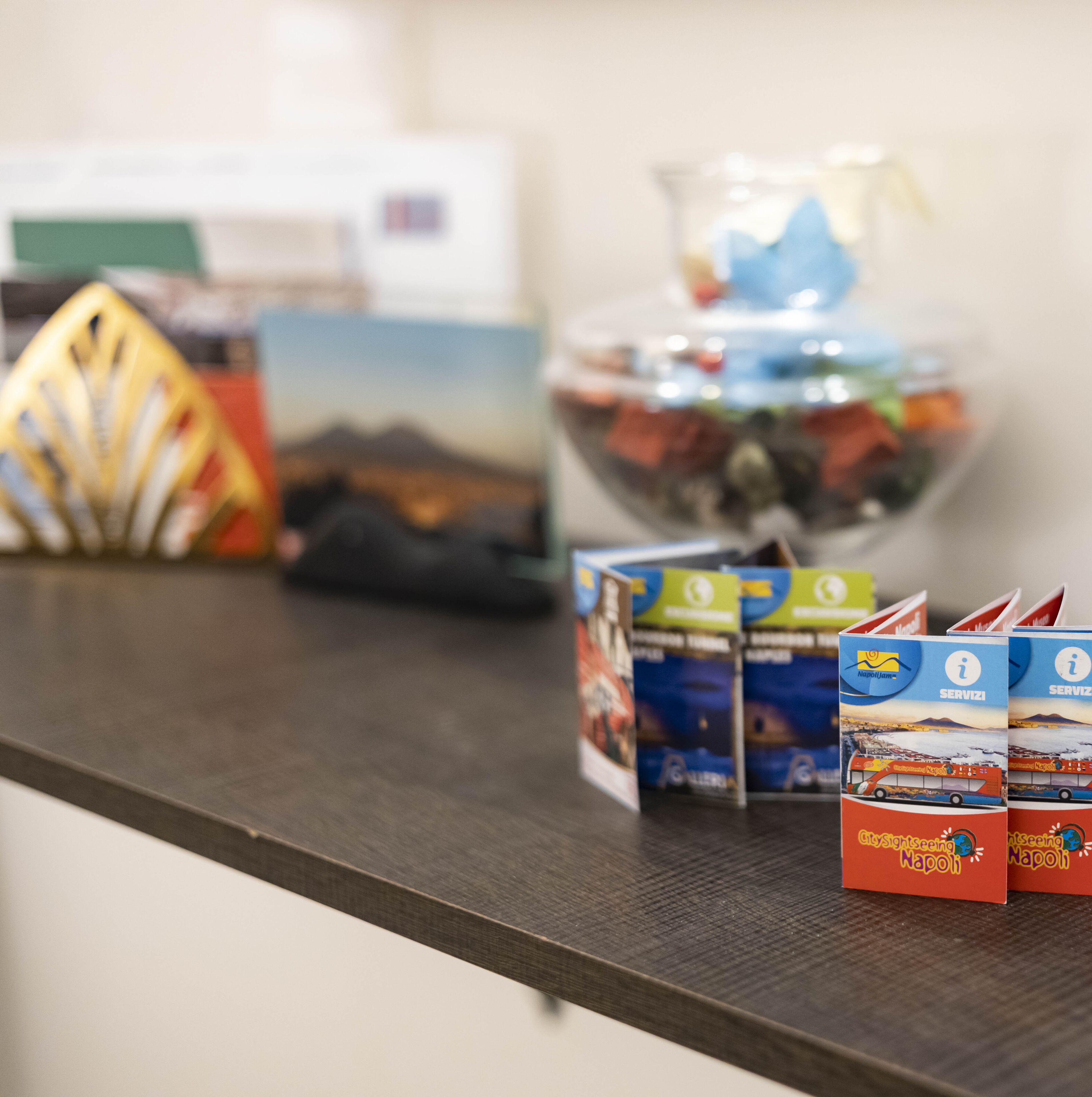 Ein Tresen mit Broschüren, einem Ventilator und einem Glasbehälter mit Snacks.