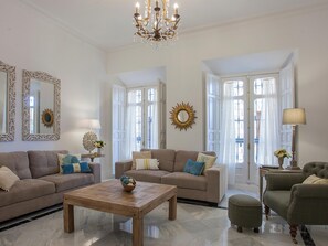 A spacious living room with a large chandelier, two sofas, a coffee table, and a side table with a lamp. - Aduana Presidential Living4malaga (Málaga)